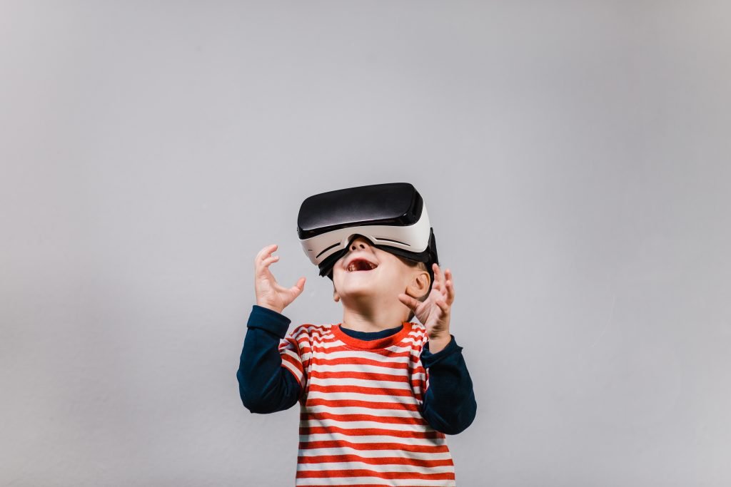 Portrait of cheerful child wearing virtual reality headset against grey background.